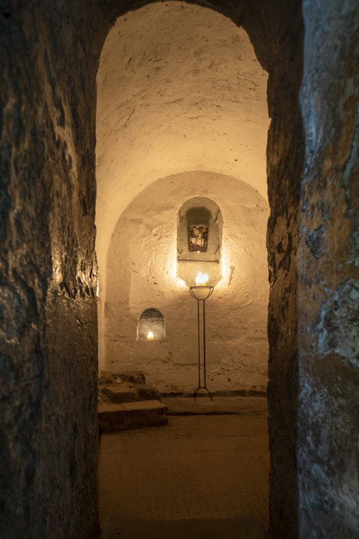 Underground stone room with arched ceiling lit by candles on a stand