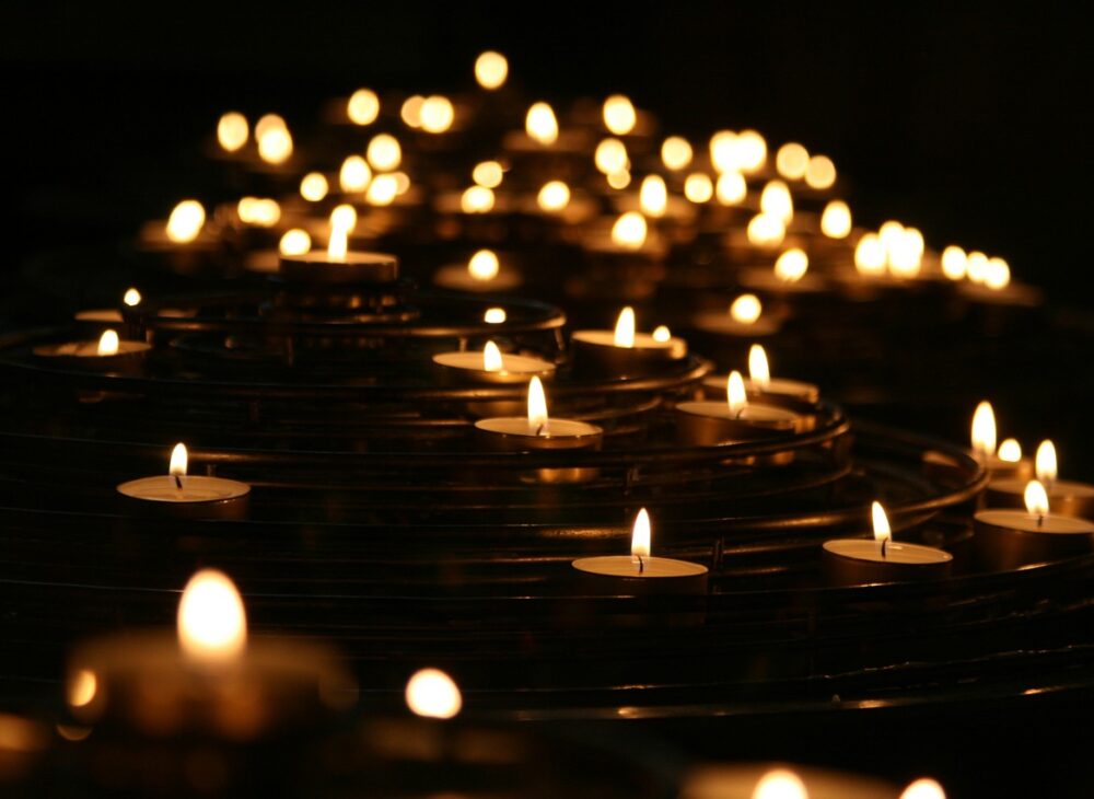 Many lit tealights with dark background